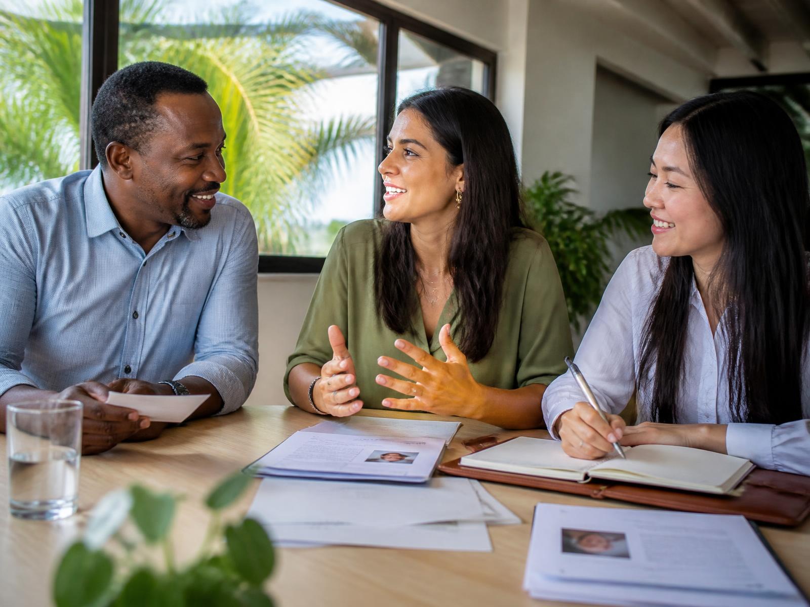 A hiring team laughing together as they review candidates around a table in a bright Caribbean office